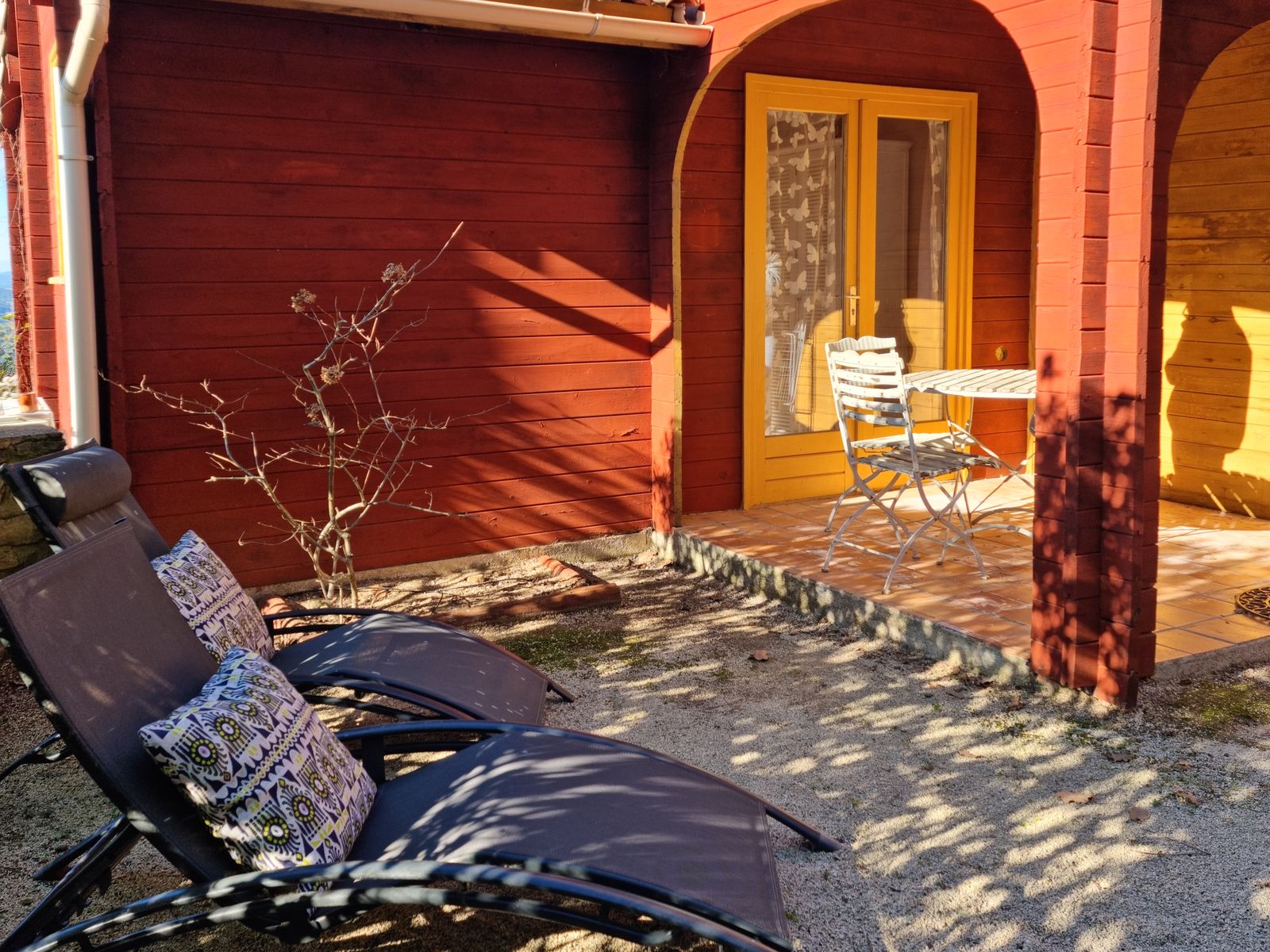 Red timber chalet with its terrace and sun loungers at La Pousterle de Sabran