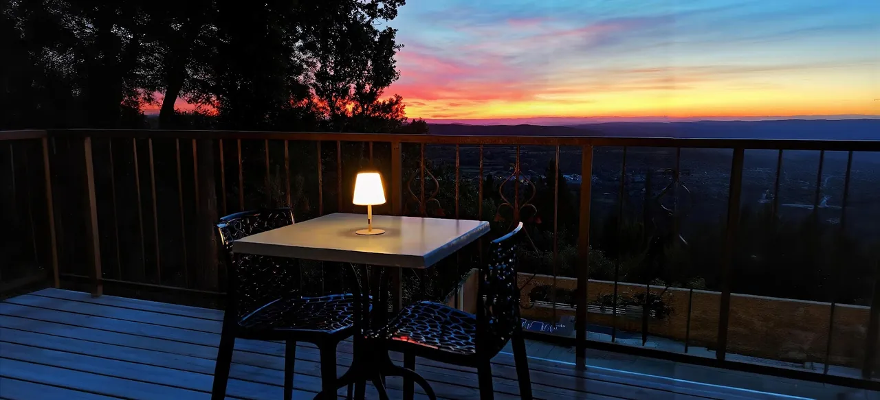 Table et lampe d'ambiance sur la terrasse du Snack au crépuscule, face à la vallée de la Cèze