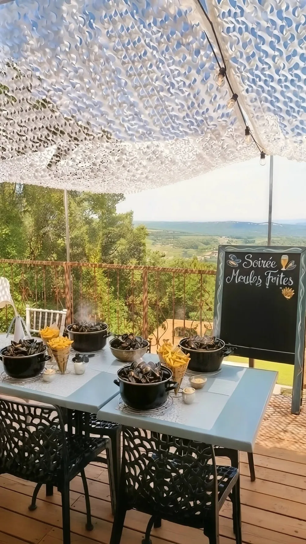 Marmites de moules et cornets de frites fumants dressés sur la terrasse du Snack de La Pousterle à Sabran, avec l'ardoise « Soirée Moules Frites » et la vue sur la vallée de la Cèze